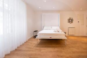 Cama en habitación con paredes blancas y suelo de madera. en DWO Ábaster Suites en Soria