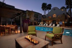 eine Terrasse mit Stühlen und einer Feuerstelle neben einem Pool in der Unterkunft Hampton Inn & Suites Phoenix/Scottsdale in Scottsdale