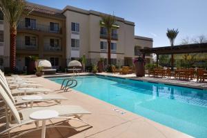 Hampton Inn & Suites Phoenix/Scottsdale في سكوتسديل: مسبح وكراسي صالة وفندق