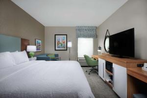 a hotel room with a bed and a flat screen tv at Hampton Inn Louisville/I-65/Brooks Road in Brooks