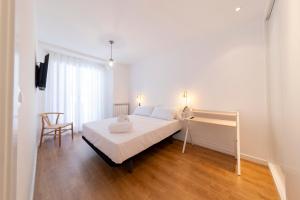 a white bedroom with a bed and a chair at Apartamentos Ábaster Suites in Soria