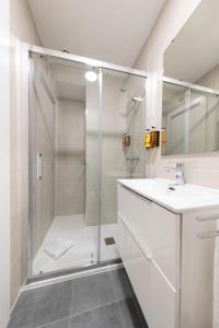 a white bathroom with a shower and a sink at Apartamentos Ábaster Suites in Soria