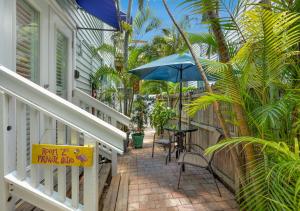 un porche con mesa y sombrilla en The Grand Guesthouse, en Key West