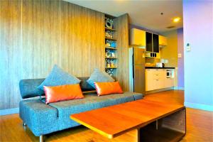 sala de estar con sofá azul y almohadas de color naranja en Nest n Rest Hotel, en Ban Bang Toei (1)