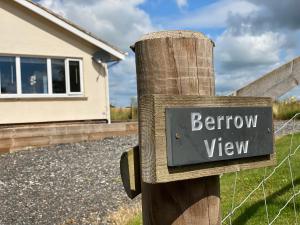 a sign on a wooden post in front of a house at Cosy bungalow with views, walks, garden & parking. in Worcester