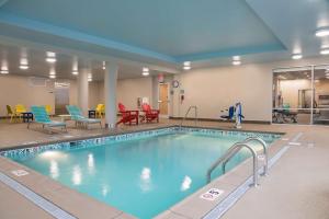 a swimming pool with chairs and tables in a building at Home2 Suites by Hilton Louisville Downtown NuLu in Louisville