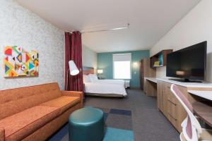 una camera d'albergo con divano, letto e TV di Home2 Suites by Hilton Louisville Downtown NuLu a Louisville