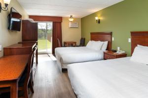 um quarto de hotel com duas camas e uma secretária em Hôtel Marineau Mattawin em Trois Rives
