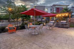 a patio with tables and chairs and red umbrellas at Home2 Suites By Hilton DuPont in DuPont