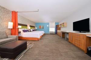 a hotel room with a bed and a flat screen tv at Home2 Suites By Hilton DuPont in DuPont
