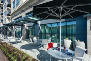 a patio with tables and chairs and an umbrella at Hampton Inn & Suites by Hilton Seattle/Northgate in Seattle