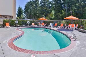 a small swimming pool with chairs and umbrellas at Hampton Inn Seattle Airport in SeaTac