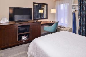a hotel room with a bed and a desk with a television at Hampton Inn Seattle Airport in SeaTac
