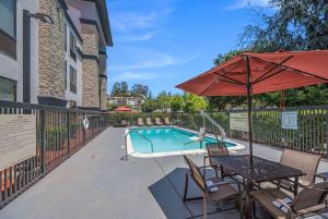 een zwembad met een tafel en een parasol bij Hampton Inn Oakland-Hayward in Hayward