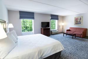 Hampton Inn & Suites Berkshires-Lenox في لينوكس: غرفه فندقيه بسرير واريكه وتلفزيون
