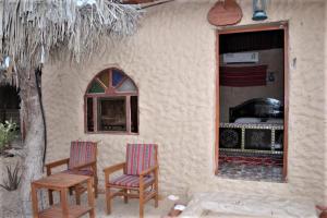 two chairs sitting outside of a house with a stove at Al Reem Desert Camp in Jalan Bani Buhassan