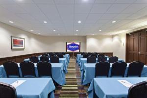 una sala de conferencias con mesas y sillas azules y una pantalla en Hampton Inn Morgan Hill, en Morgan Hill