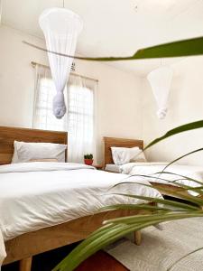 1 dormitorio con 2 camas con sábanas blancas en Goodtimewithfar House, en Moshi