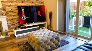 a living room with a television and a ottoman at Bridgefield House in Ashford