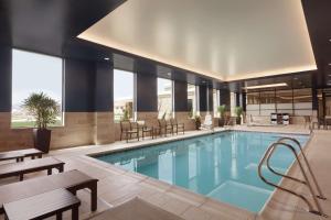 uma piscina num hotel com mesas e cadeiras em Embassy Suites By Hilton South Jordan Salt Lake City em South Jordan