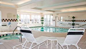 una piscina con sillas blancas, una mesa y una piscina en Hilton Garden Inn Salt Lake City/Layton, en Layton