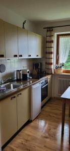 a kitchen with white cabinets and a sink and a table at Ferienwohnung Almruhe mit Pool und Sauna & direkt am Skilift in Missen-Wilhams