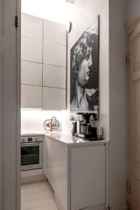 a white kitchen with a picture of a woman on the wall at 2ndhomes Stylish Studio in Helsinki Design District in Helsinki