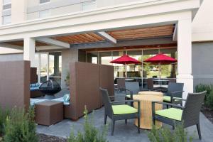 un patio avec des tables, des chaises et des parasols rouges dans l'établissement Home2 Suites by Hilton Lehi/Thanksgiving Point, à Lehi