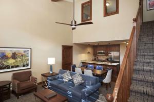 Hilton Grand Vacations Club Sunrise Lodge Park City في بارك سيتي: غرفة معيشة مع أريكة زرقاء ومطبخ