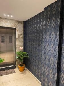 a bathroom with a blue patterned wall with a plant at HOTEL VENUS in Veraval