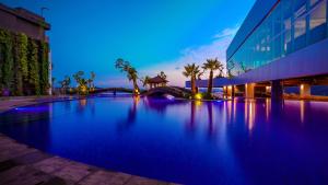 ein großer Pool vor einem Gebäude in der Nacht in der Unterkunft FUGO Hotel Samarinda in Samarinda