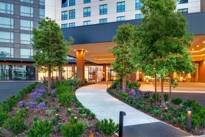 a walkway in front of a building with trees and flowers at Home2 Suites By Hilton Anaheim Resort in Anaheim