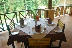 a wooden table with glasses and napkins on a balcony at Bopath Falls Rock Chalets in Agalawatta