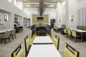 a dining room with tables and chairs and a tv at Hampton Inn & Suites Irvine/Orange County Airport in Irvine