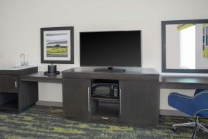 a living room with a tv and a desk with a television at Hampton Inn & Suites Irvine/Orange County Airport in Irvine