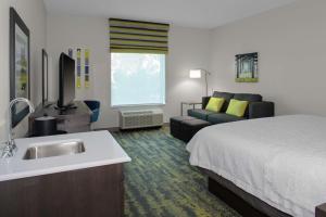 a hotel room with a bed and a sink and a couch at Hampton Inn & Suites Irvine/Orange County Airport in Irvine