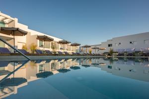 a pool with chairs and umbrellas next to a building at Mirage Bleu Hotel in Tragaki