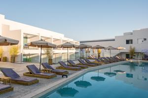 una piscina dell'hotel con sedie a sdraio e ombrelloni di Mirage Bleu Hotel a Tragaki