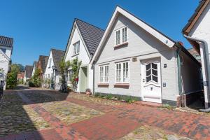 uma fila de casas brancas numa rua de tijolos em Der kleine Carl em Wyk auf Föhr