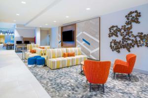 Hilton Garden Inn Brunswick في برونزويك: غرفة معيشة مع كنب وكراسي برتقال