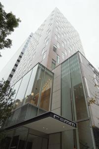 un edificio de cristal alto con un cartel. en remm Hibiya, en Tokio