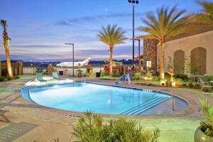 a swimming pool with palm trees and a building at Home2 Suites By Hilton St. Simons Island in Saint Simons Island