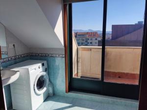 baño con lavadora y ventana en Los Abriles, en Baiona