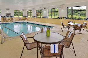 a pool with tables and chairs next to a pool at Hampton Inn & Suites St. Louis - Edwardsville in Glen Carbon