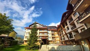 a large building with a tree in front of it at private apartment hotel Regnum Bansko in Bansko