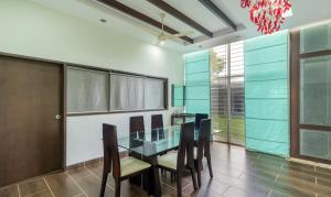 a dining room with a glass table and chairs at Treebo Trend Midvalley Residence in Yelagiri
