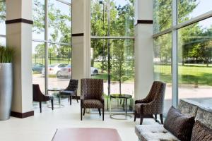 um átrio com cadeiras, mesas e janelas em Embassy Suites by Hilton St Louis Airport em Bridgeton