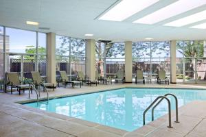una piscina con sillas y mesas en un edificio en Embassy Suites by Hilton St Louis Airport, en Bridgeton