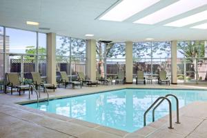 a swimming pool with chairs and tables in a building at Embassy Suites by Hilton St Louis Airport in Bridgeton