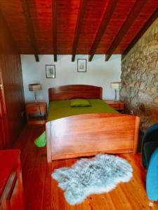 um quarto com uma cama de madeira e um tapete peludo em CASA DE MADEIRA E PEDRA em Afife